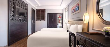 Quarto de hotel com uma cama grande, uma escrivaninha, uma cadeira, cômoda, espelho e janela com persianas.
