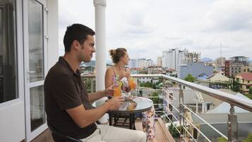 A balcony with a city view, a glass door, and a table with drinks.