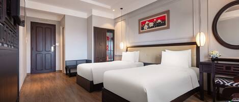 Habitación de hotel con dos camas, un banco, un escritorio, un espejo y un cuadro en la pared.