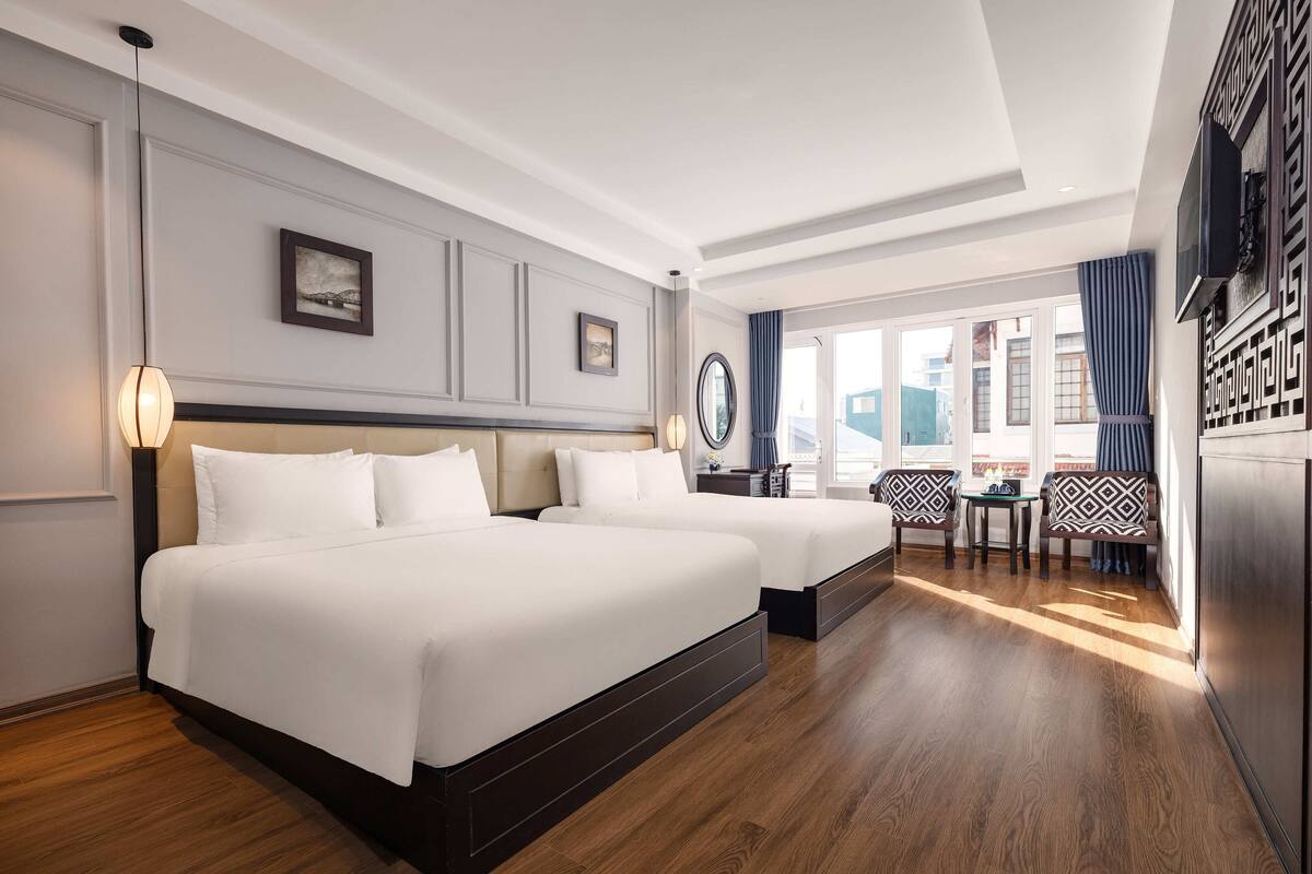 A hotel room with two beds, a desk, and a chair.