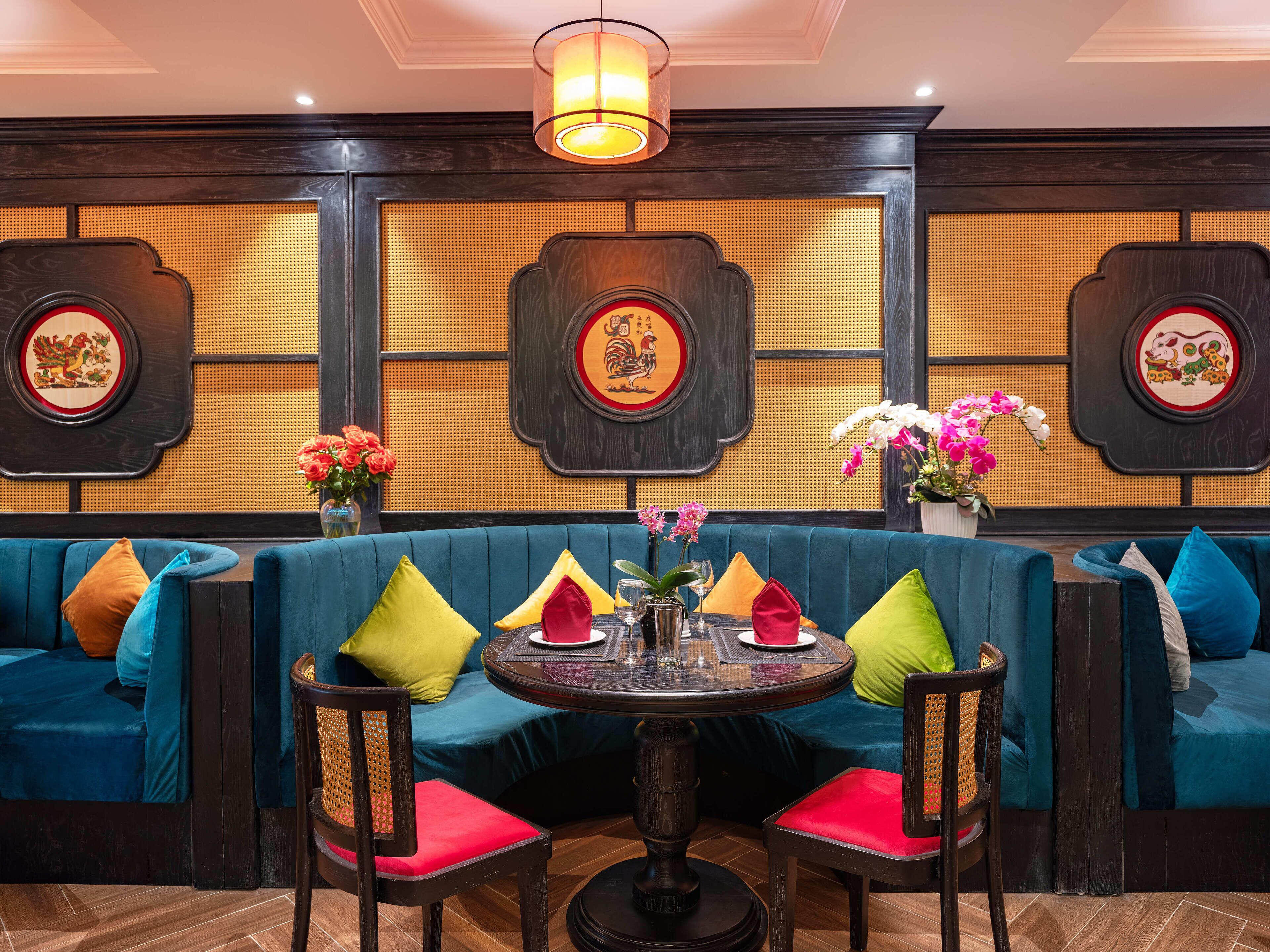 A restaurant with a blue upholstered booth seating, a round table with chairs, and decorative wall panels.