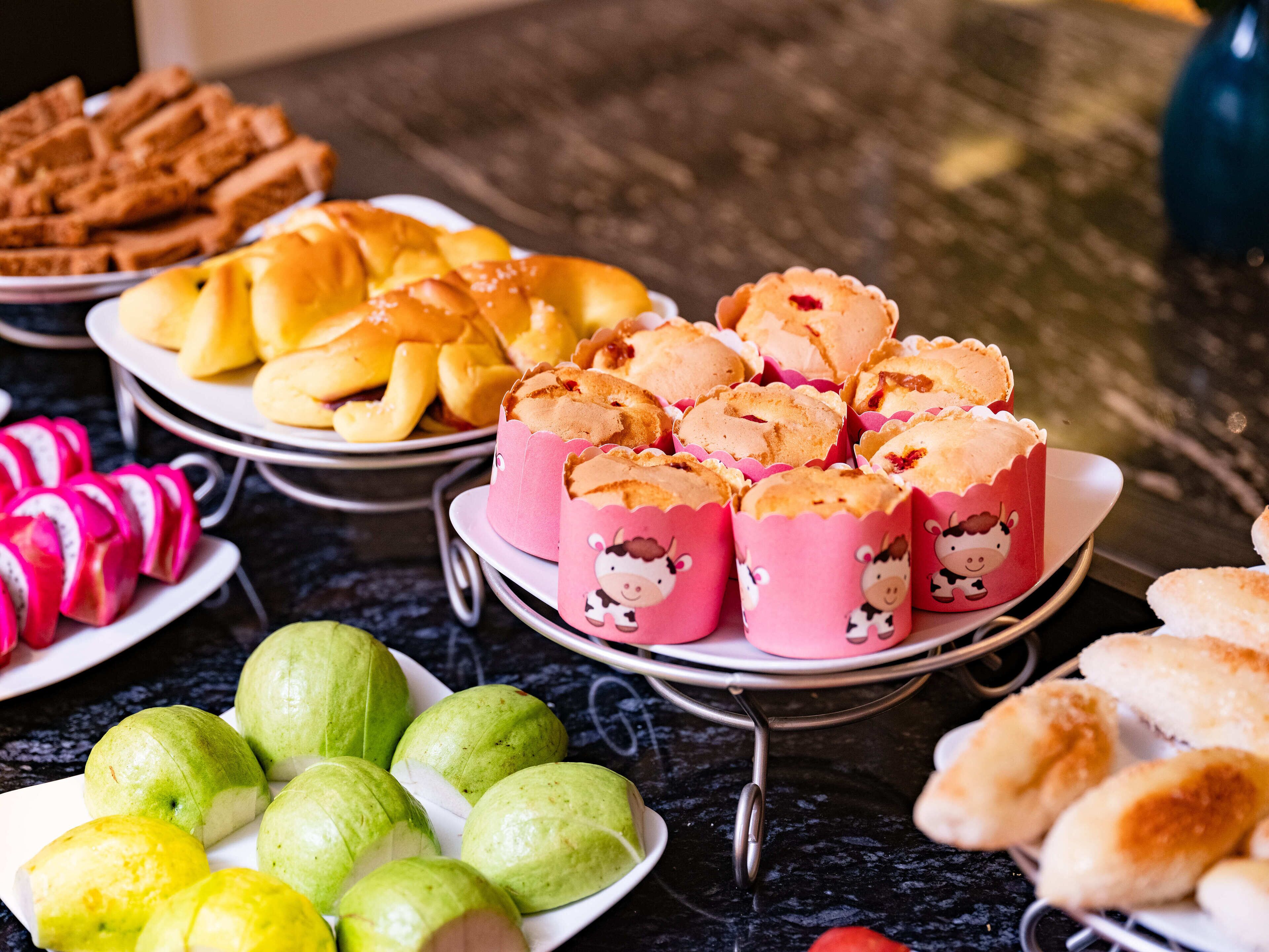 A buffet with various food items including pastries, fruits, and bread.