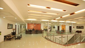 A hotel lobby with a reception desk, seating area, staircase, and a polished floor. - Hotel Grand Mumtaz Towers (Srinagar)