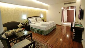 A hotel room with a bed, a sofa, a small table, and a TV. - Hotel Grand Mumtaz Towers (Srinagar)