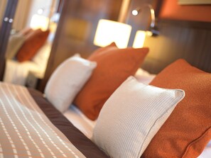 Une chambre d’hôtel avec un lit bien fait, des oreillers et une lampe.