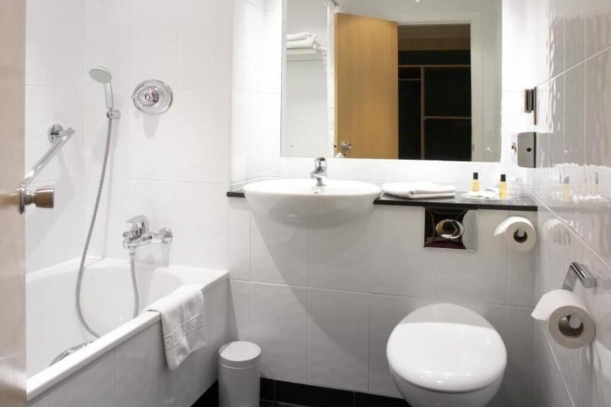 A modern bathroom with a bathtub, sink, toilet, and a mirror.
