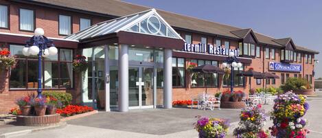 A Termil Restaurant with a modern glass entrance, outdoor seating, and flower arrangements.