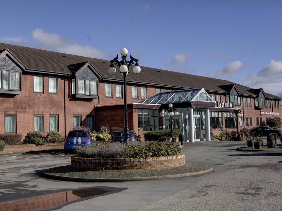 Un hôtel avec une façade en briques, une entrée en verre et un parking.
