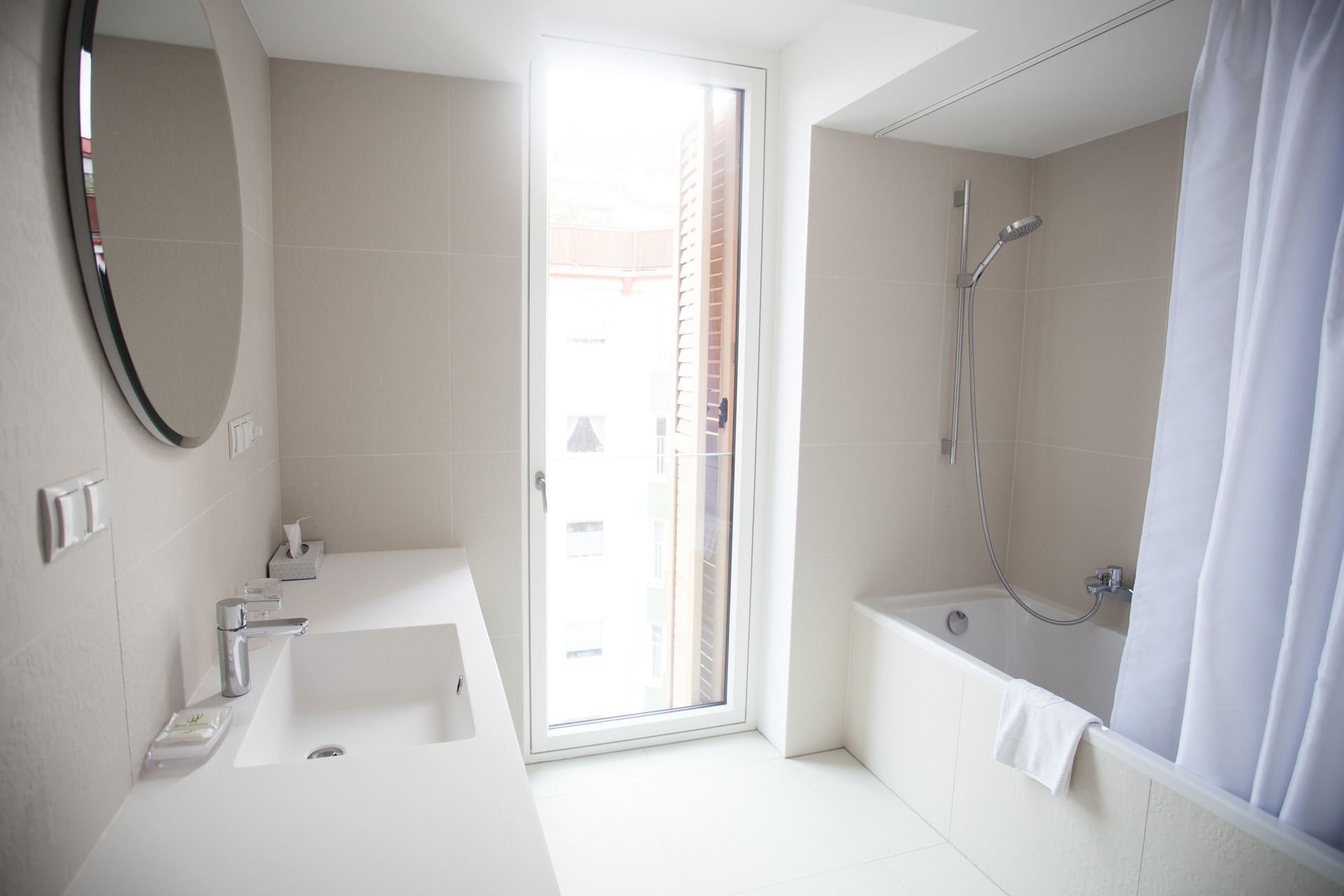 A modern bathroom with a large window, a bathtub, and a shower.