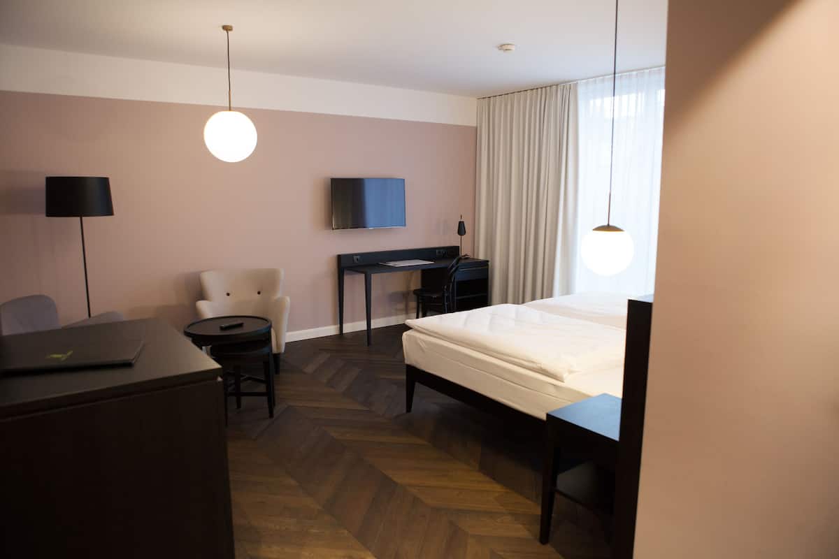 Una habitación de hotel con cama, escritorio, silla y televisión.