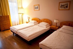Quarto de hotel com duas camas de solteiro, cabeceiras de madeira, cômoda de madeira e duas luminárias de cabeceira.