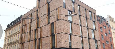 A multi-story building with a modern brick facade, large windows, and a ground-level commercial space.