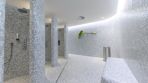 Un baño moderno con paredes y suelo de mosaico, una zona de ducha y un banco.
