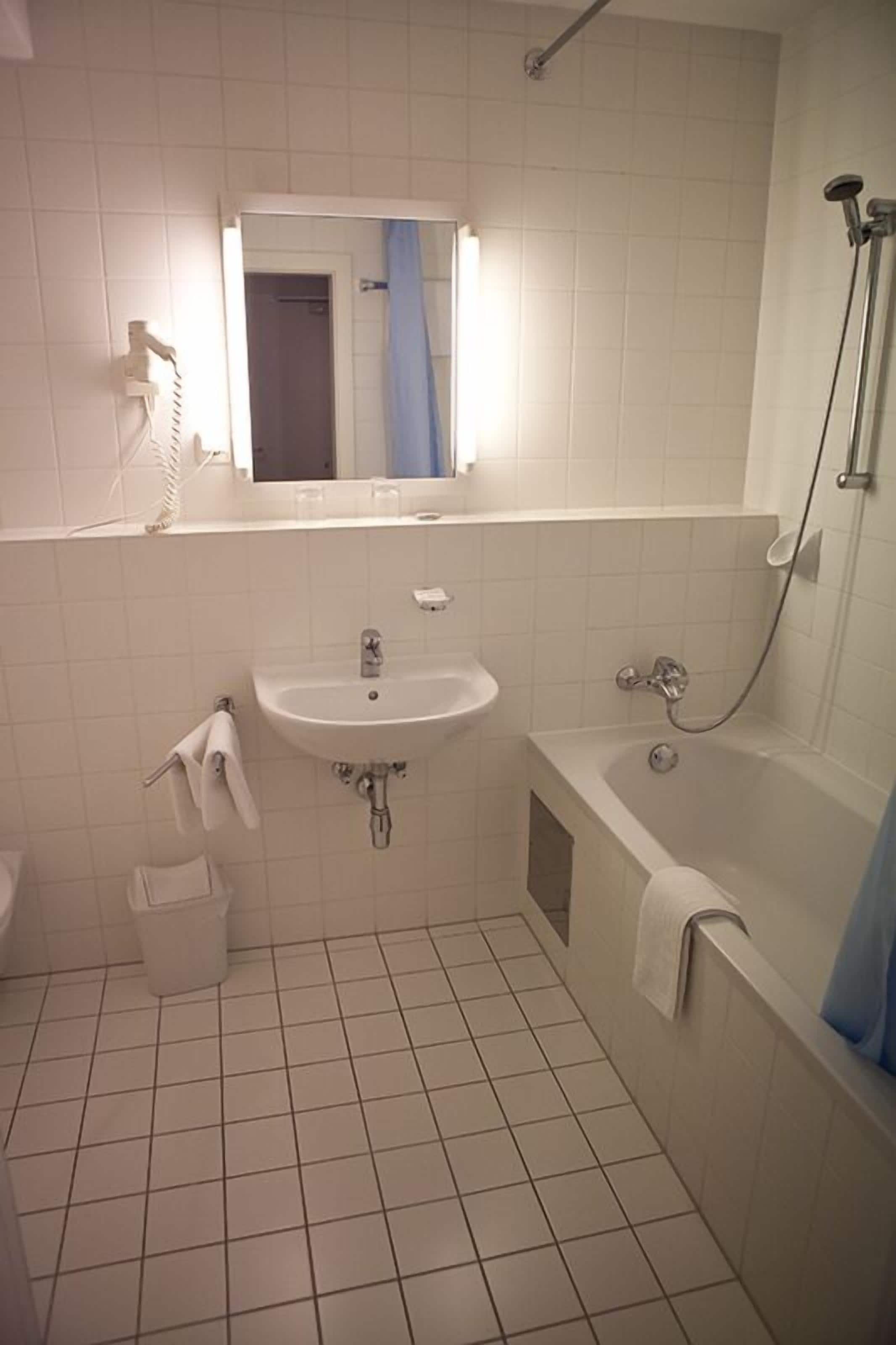 A small, clean bathroom with a sink, mirror, and shower.