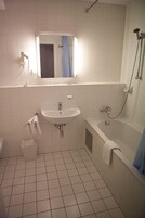 Un bagno piccolo e pulito con lavandino, specchio e doccia.