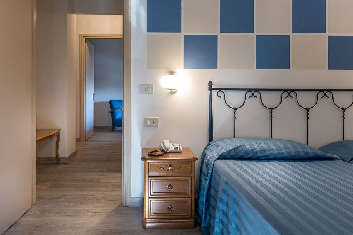 Un dormitorio con cama, mesita de noche y pared con diseño geométrico.