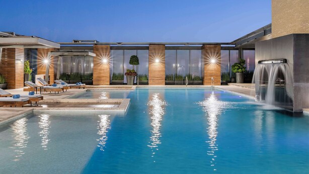 A swimming pool with lounge chairs and a waterfall feature. - Hilton Mexico City Santa Fe (Mexico City)