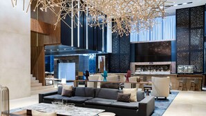 A modern lobby with a large sofa, a coffee table, and a bar area with seating. - Hilton Mexico City Santa Fe (Mexico City)