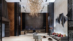 A modern lobby with a central seating area, a decorative chandelier, and a reception desk. - Hilton Mexico City Santa Fe (Mexico City)