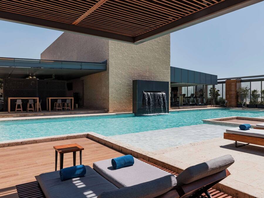 A modern pool area with lounge chairs, a waterfall feature, and a bar area.