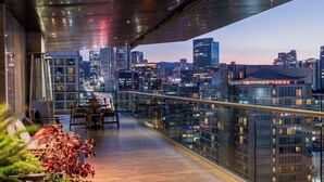 A modern balcony with a city view, wooden flooring, and a glass railing. - Hilton Mexico City Santa Fe (Mexico City)