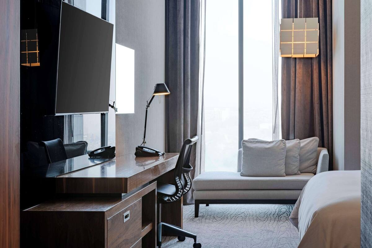 Una habitación de hotel con un escritorio de madera, una silla, un sofá y una cama.