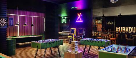 Une salle de billard équipée de tables de baby-foot, d’un jeu de fléchettes et d’une table de billard.