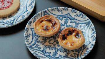 A table with two plates of Portuguese custard tarts, a cup of tea, and a glass of water on a tray.