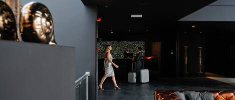 Un hall d’entrée moderne avec un canapé en cuir, une femme qui marche et un homme avec une valise.