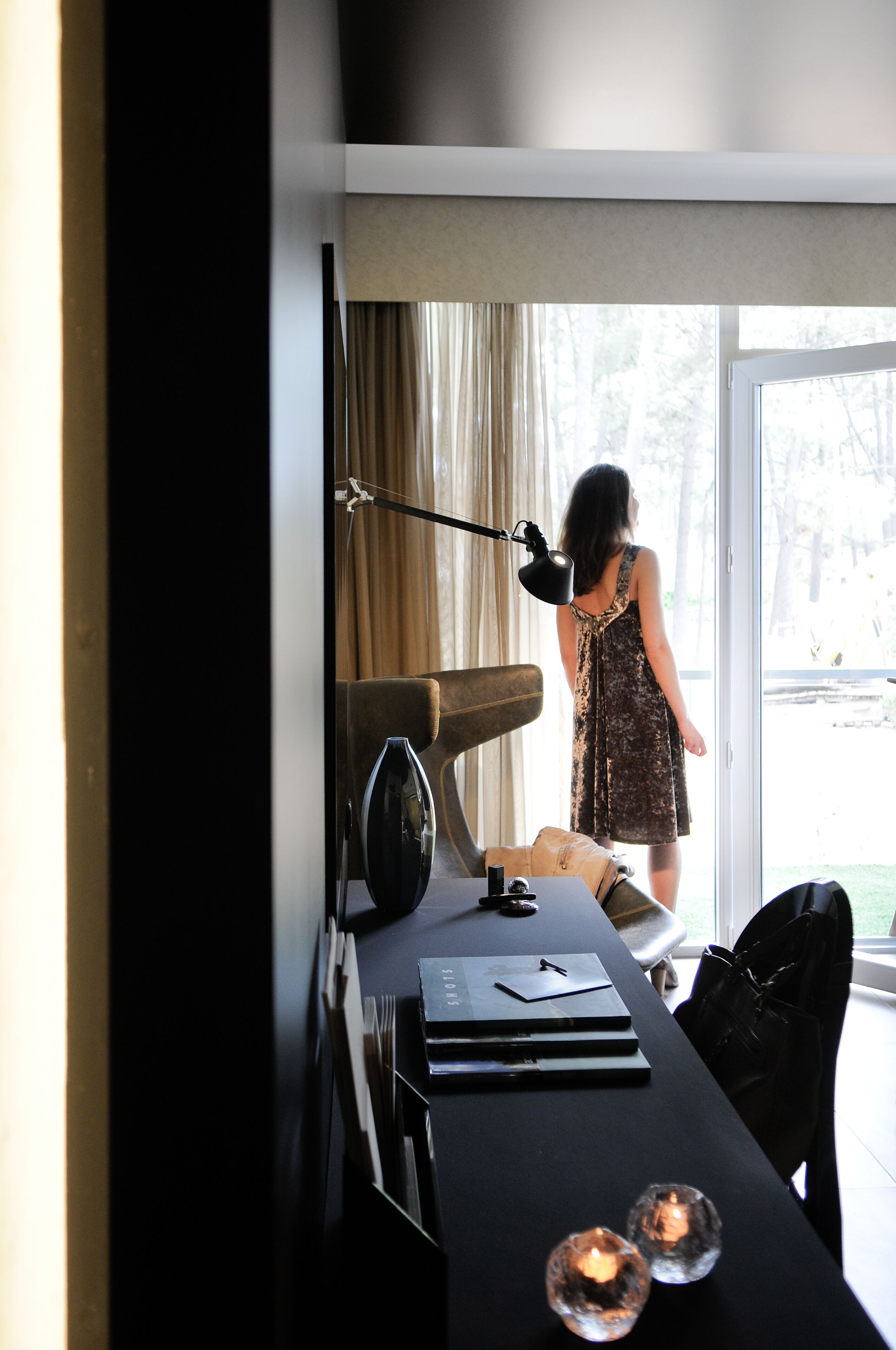 A room with a desk, a chair, a lamp, and a view of the outdoors.