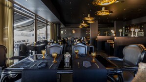 Un restaurant avec des tables dressées, un éclairage installé au plafond et une vue dégagée sur l’extérieur grâce à de grandes fenêtres.