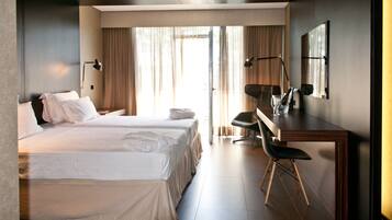 A hotel room with a large bed, a desk, a chair, and a mirror.