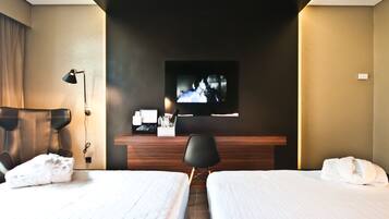 A hotel room with two beds, a TV mounted on the wall, a desk, and a chair.