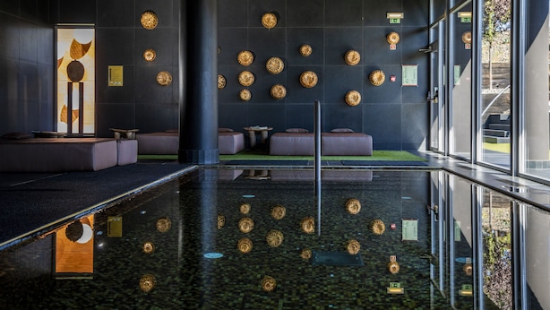 Un hall d’entrée moderne doté d’un sol réfléchissant, d’espaces aménagés pour s’asseoir et d’éléments décoratifs sur les murs.