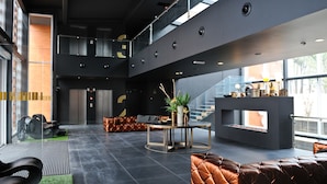 Un hall d’entrée spacieux avec un plafond haut, un espace salon central et un escalier menant à un niveau supérieur.