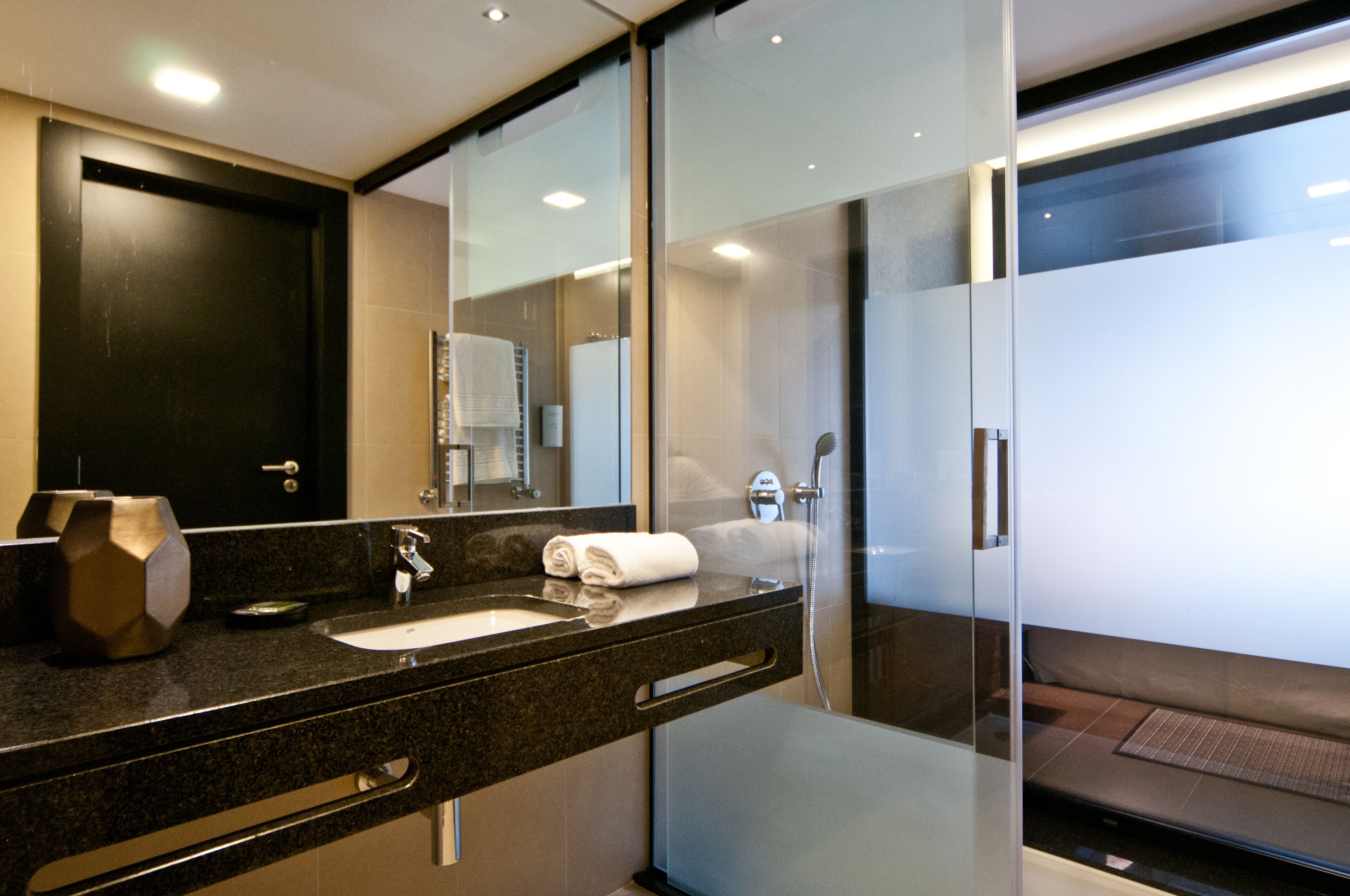 Een moderne badkamer met een douchecabine van glas, een wastafel met een handdoek en een donkere badkamerkast.