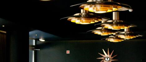 Interior de restaurante con múltiples lámparas colgantes, un adorno de pared con forma de estrella y señalización de salida de incendios visible.