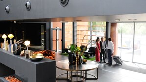 Un hall d’entrée moderne avec un comptoir d’accueil, un espace salon et de grandes fenêtres.