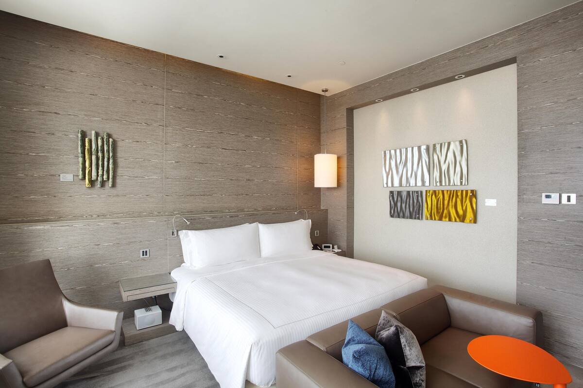 Une chambre d’hôtel moderne avec un grand lit, un canapé, une petite table et une œuvre d’art accrochée au mur.