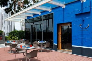 An outdoor seating area with tables and chairs, a glass door entrance, and a blue wall with the word 'escape' on it.