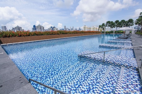 Una piscina al aire libre, sombrillas, sillones reclinables de piscina