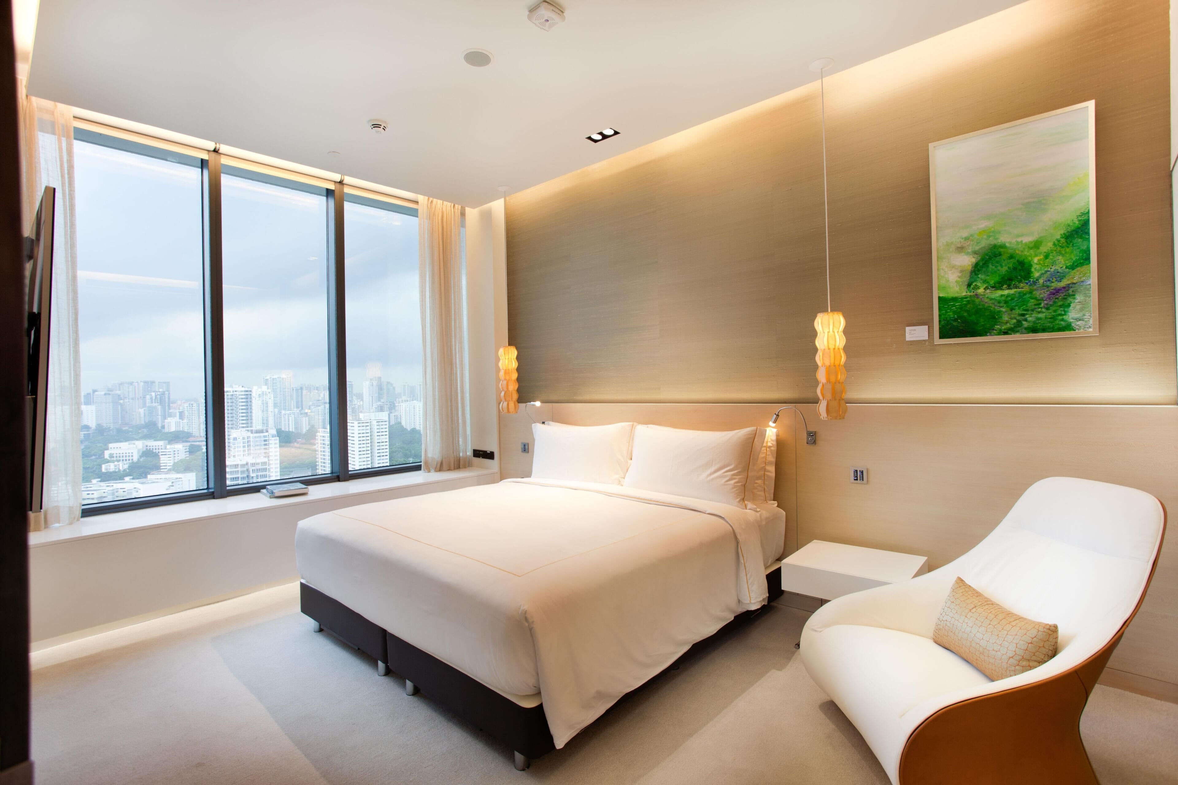 Ein modernes Hotelzimmer mit einem großen Bett, einer Sitzecke und Blick auf die Stadt.