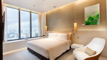 Ein modernes Hotelzimmer mit einem großen Bett, einer Sitzecke und Blick auf die Stadt.