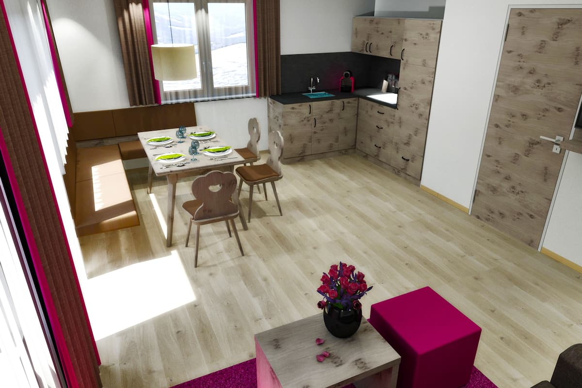 A compact kitchen with a dining area, a small table with a vase of flowers, and a pink ottoman.