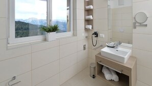 Et moderne badeværelse med et vindue, en vask, et spejl og en håndklædestang.