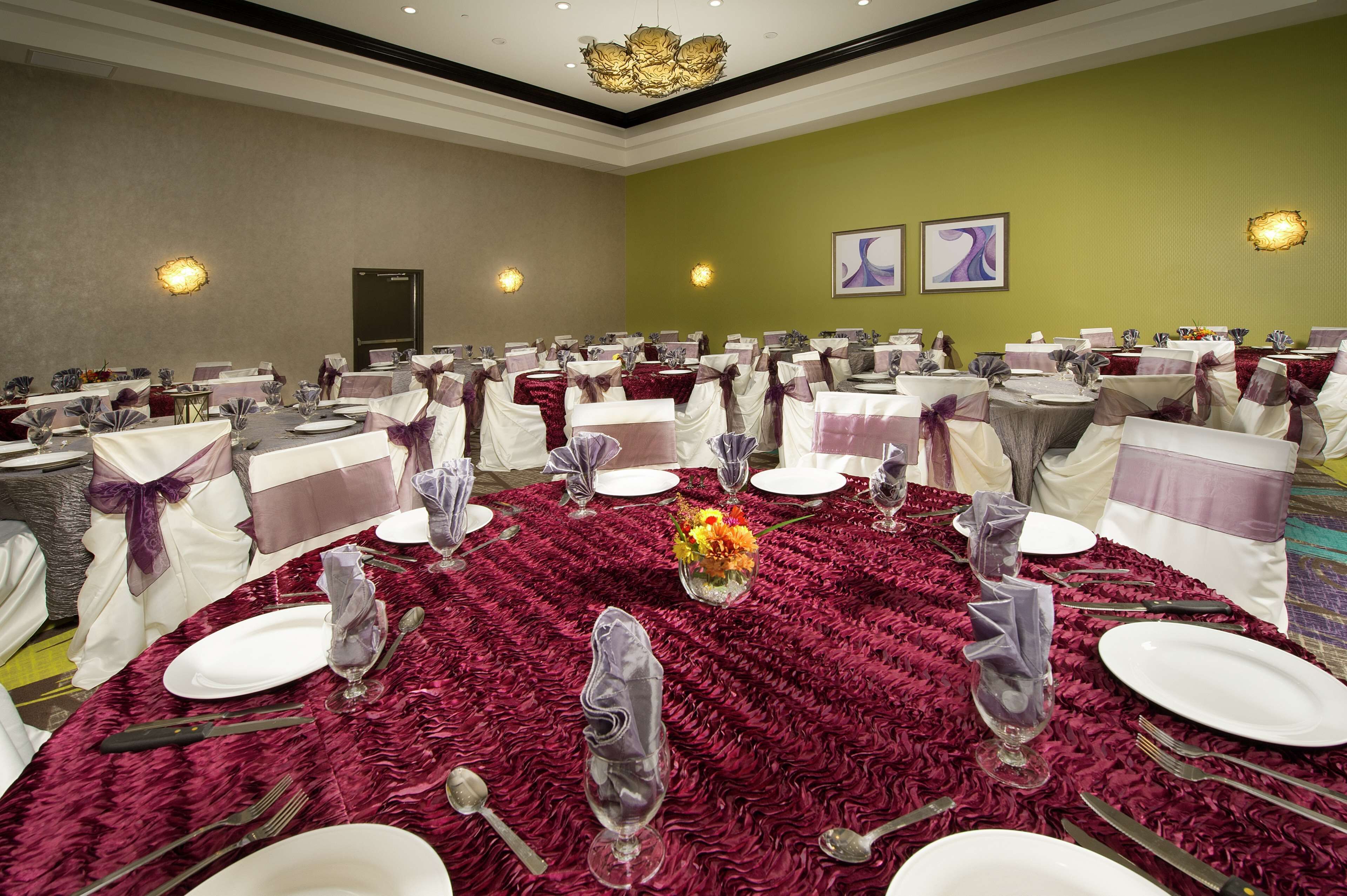 A banquet hall with round tables set for dining, featuring white tablecloths and purple sashes.