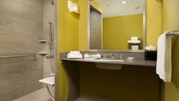 Un baño moderno con ducha, lavamanos y espejo.