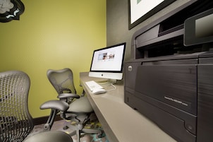 Un escritorio con una computadora de escritorio, una impresora y dos sillas de oficina.
