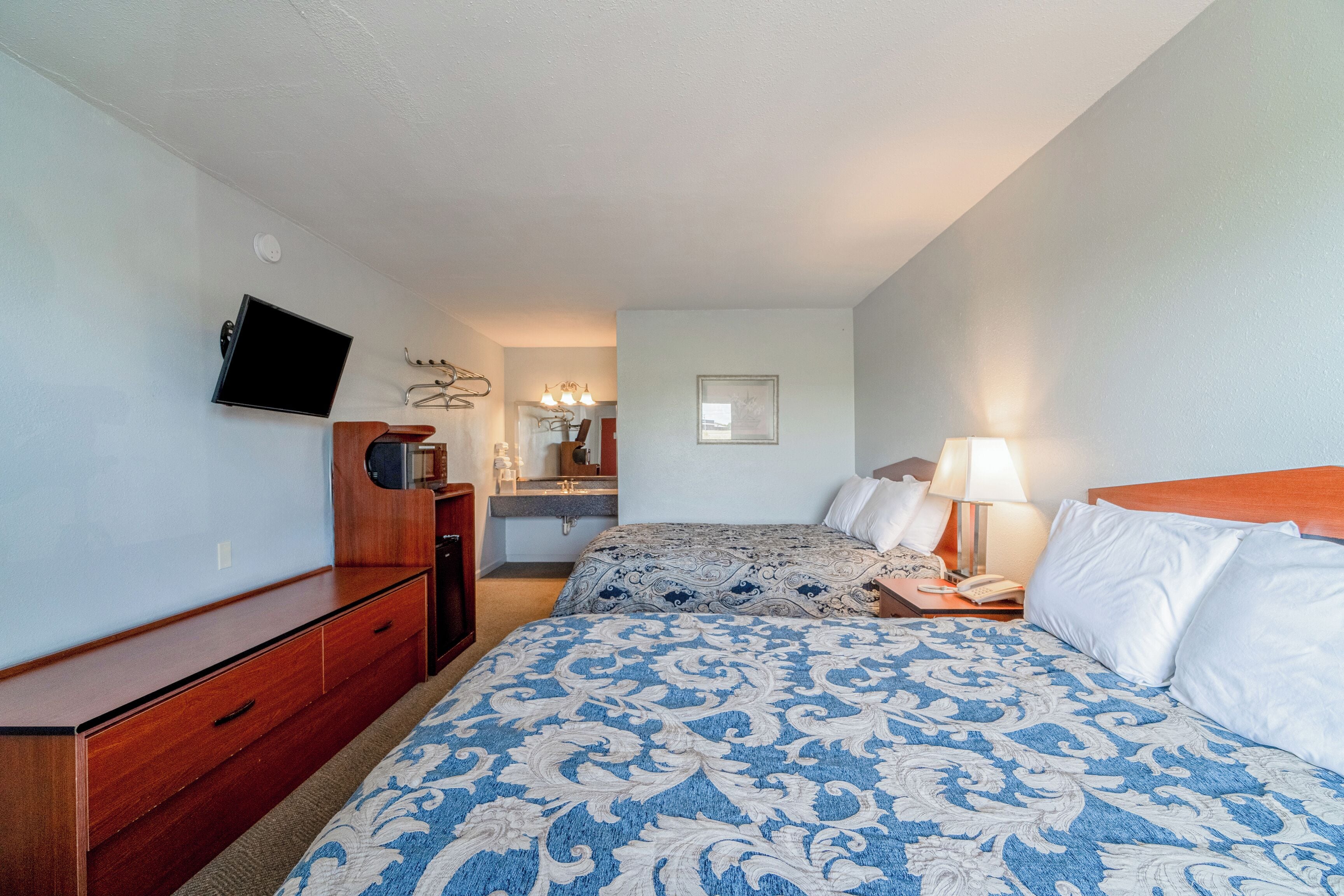 Habitación de hotel con cama, televisión, cómoda y baño a la vista.