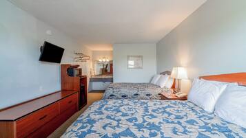 Habitación de hotel con cama, televisión, cómoda y baño a la vista.